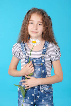 Girl posing with daisies isolated on blue backgroundの写真素材