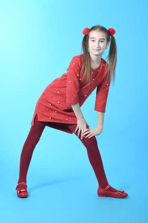 Full length studio photo girl wearing red dress standing on blue background.の写真素材
