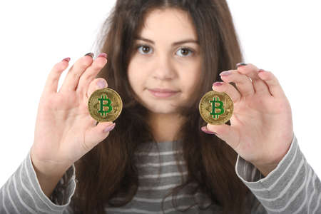 Pretty Girl holding new golden cryptocurrency bitcoin in hands on white background. Concept of bitcoin grows in priceの写真素材
