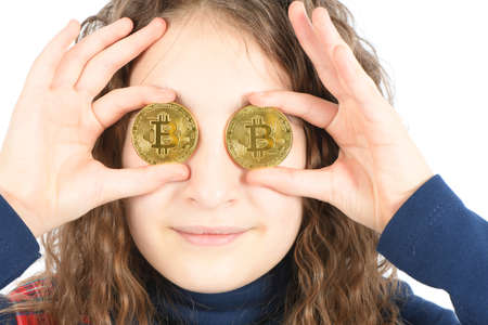 Happy girl with long curly hair keeps the eye instead two silver cryptocurrency bitcoin in hands on white background. High resolution photo. Full depth of field.の写真素材
