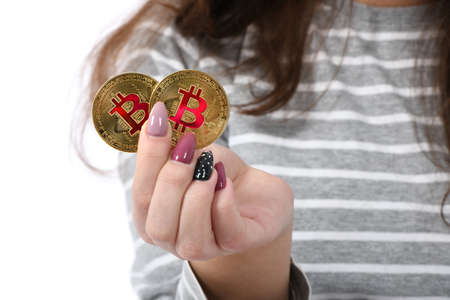 Pretty Girl holding in front of her two golden cryptocurrency bitcoin in hands on white background. Concept of bitcoin falls in priceの写真素材
