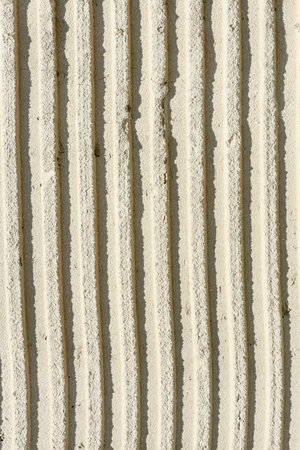 Background of old tile adhesive on wall being repaired. Abstract pattern of notched trowel. High...