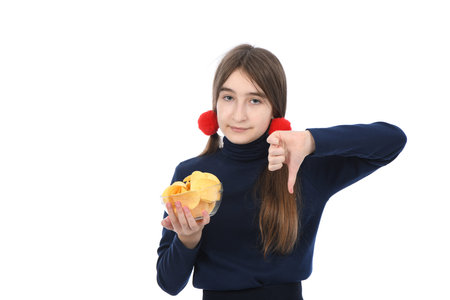 Pre-adolescent girl holding bowl is full of potato chips. Isolated on white background. High resolution photo. Full depth of field. Concept of choosing eat junk food.の写真素材