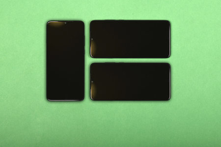 Black mobile smartphone with blank screen. Isolated on green background. High resolution photo. Full depth of field.の写真素材