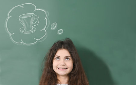 Pre-adolescent girl measuring her height on drawn chalk height meter. Girl is behind the school board background. High resolution photo. Full depth of field.の写真素材