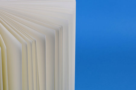 Fan unfold open small notepad with blank light pages. Blue background. High resolution photo. Full...
