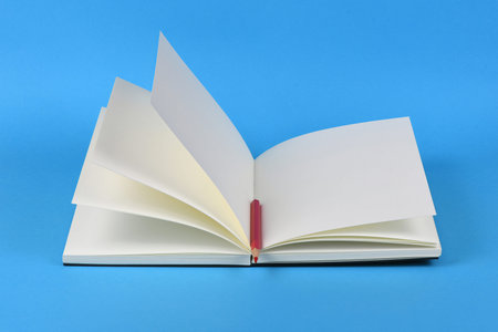Side view of workplace with pencil on notebook on blue background. High resolution photo. Full depth...