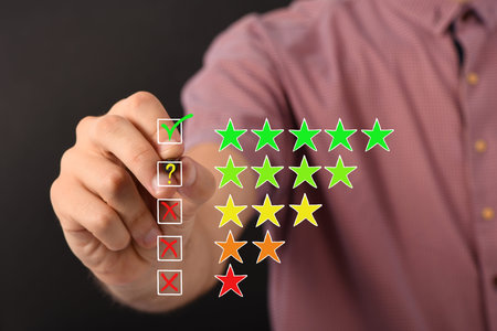 Man hand putting check mark a checkbox on five star rating on black background. High resolution...