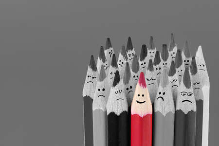 Bright colored smiling pencil among big set of black and white sad pencils. Close up macro shot. High resolution photo. Full depth of field.の写真素材