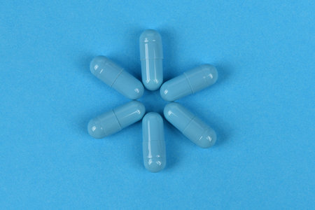Blue medical capsules pill on blue background. High resolution photo. Full depth of field.の写真素材