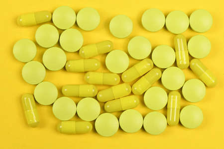 Pharmaceutical tablets, medicine for people's health to heal diseases. Yellow tablets on yellow background. High resolution photo. Full depth of field.の写真素材