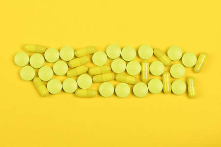 Pharmaceutical tablets, medicine for people's health to heal diseases. Yellow tablets on yellow background. High resolution photo. Full depth of field.の写真素材