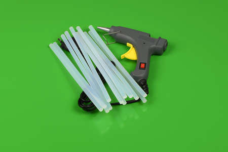 Electric hot glue gun with glue stick isolated on green background. High resolution photo. Full depth of field.の写真素材