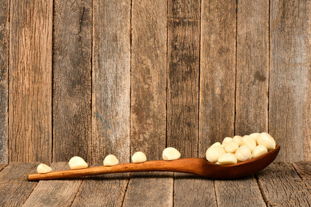 Pile of fresh garlic cloves in wooden spoon, isolated on dark wood background. High resolution photo. Full depth of field.の写真素材