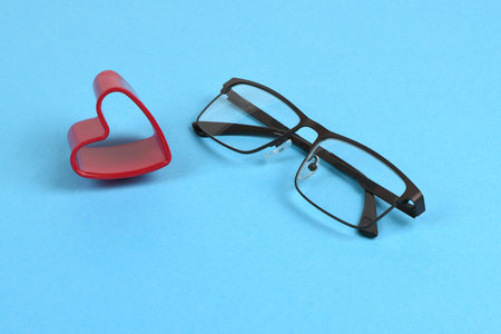 Reading glasses with heart on the side. Concept of the convenience of wearing glasses isolated on blue background. High resolution photo. Full depth of field.の写真素材