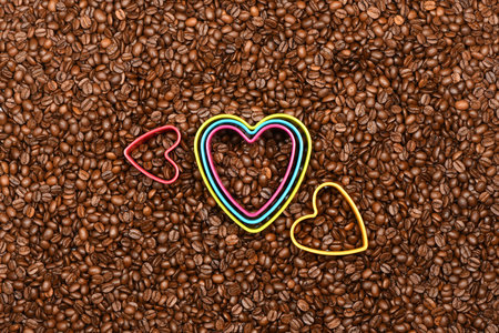 Multicolored hearts in roasted coffee beans background top view. High resolution photo. Full depth of field.の写真素材
