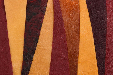 Top view of colorful fruit leather strips arranged vertically. Healthy dried fruit pastila snack texture background.の写真素材
