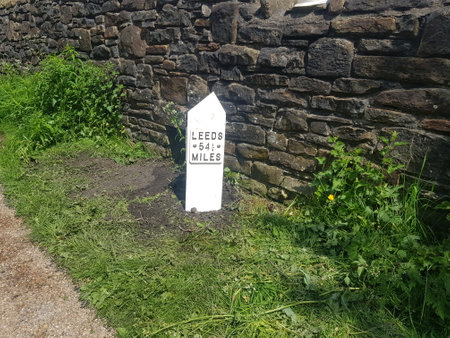 A  mile marker in front of old style stone wallの写真素材