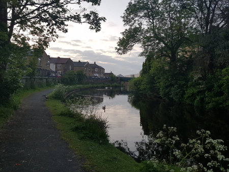 A scenic view of the canal on a summer evening with houses and a cloud speckled skyline in the...