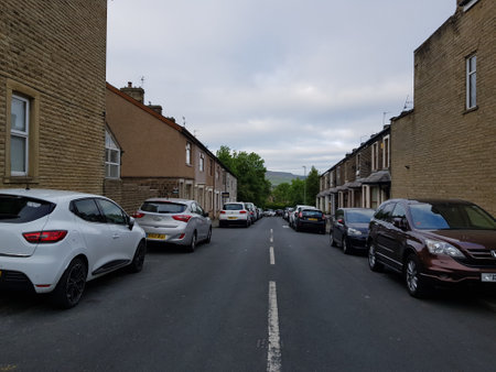 A row of cars parked on a side street with rows of terraced housing disappearing into a foliage filled natural background.の写真素材