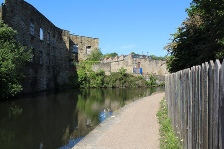 Beautiful summer scene with derelict factories backing on to the canal under a beautifully blue sky in the morning.の写真素材