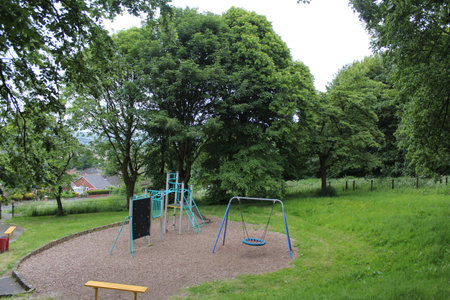 Scenic summer view of the playground in a public park, rich, foliage filled background under a...