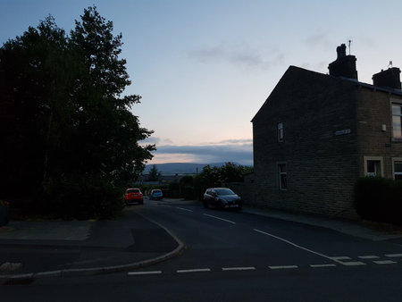 Sunrise from a village in the English countryside with houses, cars and foliage in front of the...