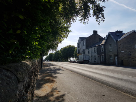 Sunlit view of the road out of town as it crests the hill on a beautiful summer morning, scenic summer townscape.の写真素材