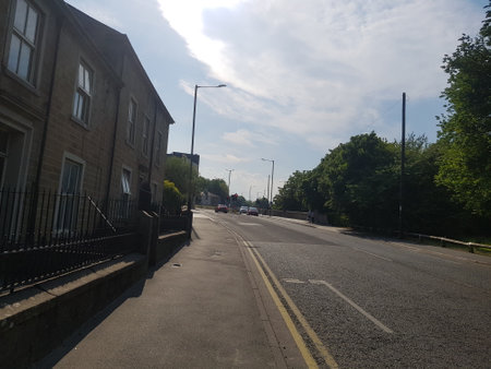 View from the main road out of town on a bright summer day with houses and trees under a stunning sunlit cloudscapeの写真素材