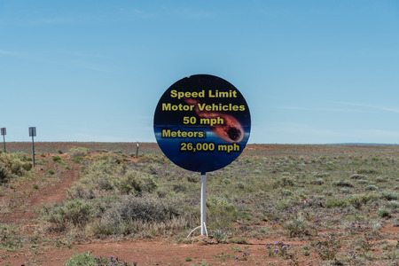 A humorous road sign in the high desert of northern Arizona near the Meteor Crater, set against the blooming desert flowersの写真素材