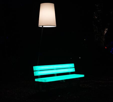 Enchanted forest of light - brightly illuminated bench in the middle of a parkの写真素材