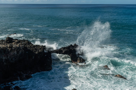 Scenic vista of waves breaking against the rocky shore along the Kaena Point trail on Oahu, Hawaiiの写真素材
