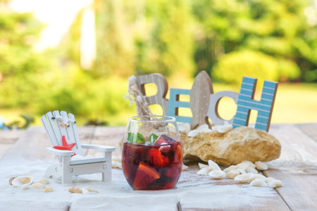 Summer red sweet dessert in outdoor scenery on wooden table with shell and sand.