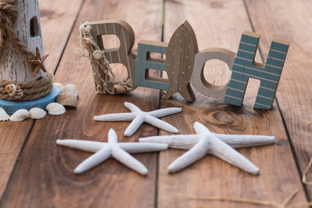 Summer beach decoration on wooden table with sand, starfish and shells.