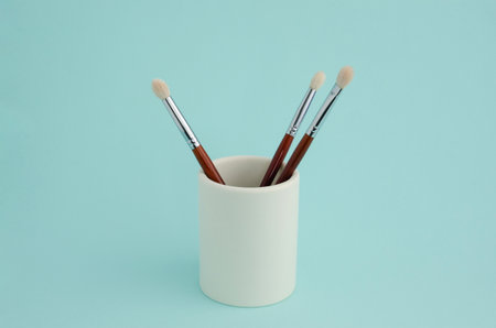 Make-up brushes in white cup on blue backgroundの写真素材