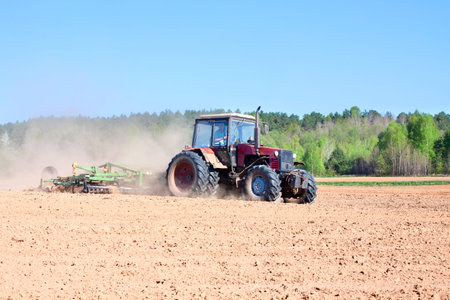Ploughing tractor during cultivation agriculture works at field with plough