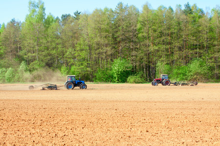 Ploughing tractor during cultivation agriculture works at field with ploughの写真素材
