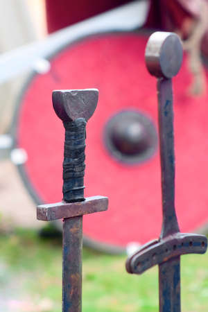 Two old swords and a shield on grassの写真素材