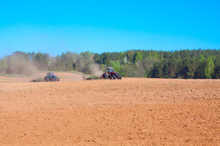 Ploughing tractor during cultivation agriculture works at field with ploughの写真素材