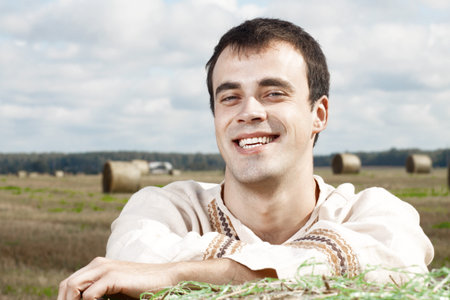 Young smiling men in national belorussian costume resting on a haystackの写真素材