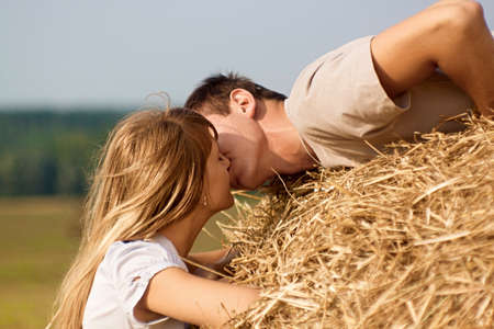 Young couple kissing on a haystack on harvested fieldの写真素材