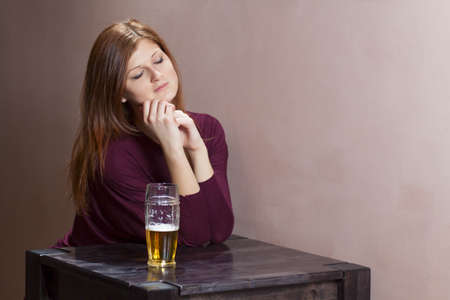lonely girl sitting at a table in the barの写真素材