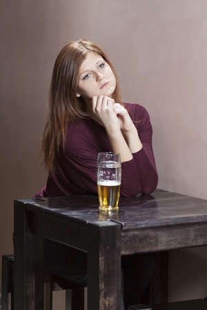 lonely girl sitting at a table in the barの写真素材