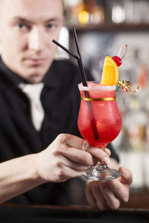 The bartender hands a freshly prepared cocktail to clientの写真素材