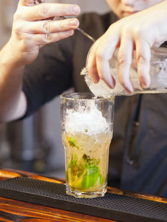 Bartender pouring ice in glass - preparing mojitoの写真素材