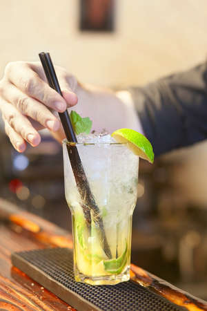 Bartender put a straw in a glass with mojitoの写真素材