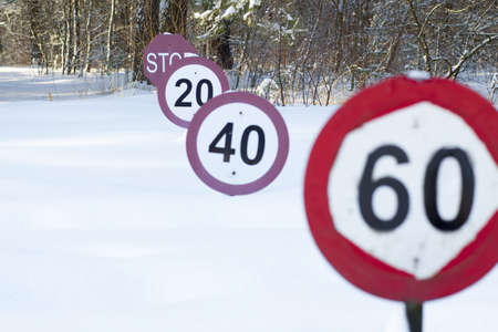 Speed limit signs under the snow on road in forestの写真素材