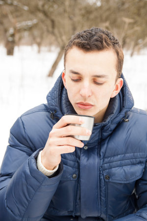 Man warming up with hot tea in cold winter time sitting