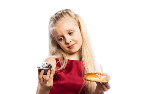Girl making a choice between two cakes. Isolated on white background.の写真素材