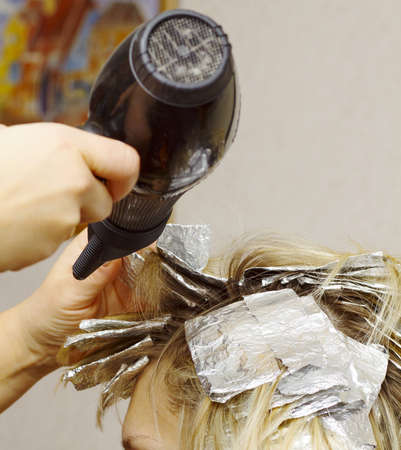 woman with coloring foil on her hair in salonの写真素材